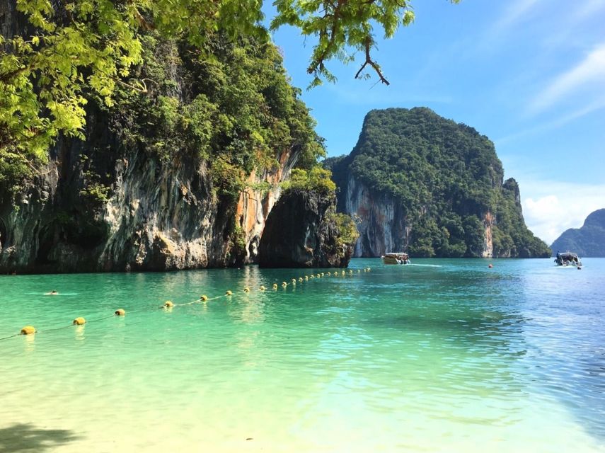 Longtail boats moored under limestone cliffs in the Hong Islands, Krabi